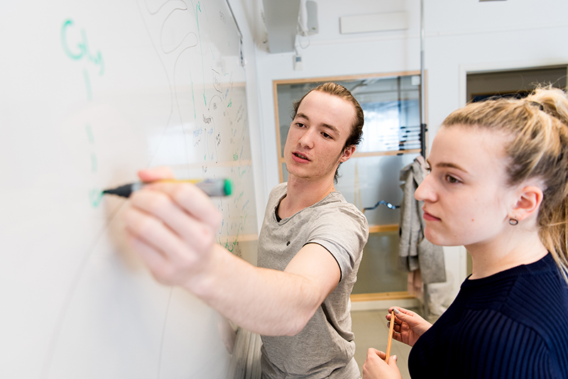 Två studenter som skriver på en whiteboard