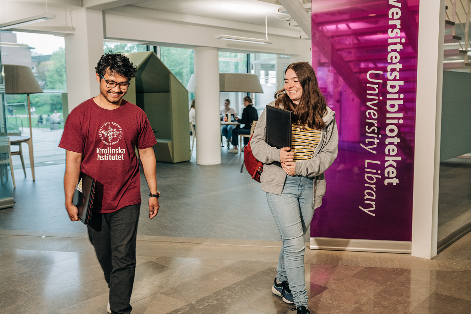 Two students outside the entrance door to the library in Solna.