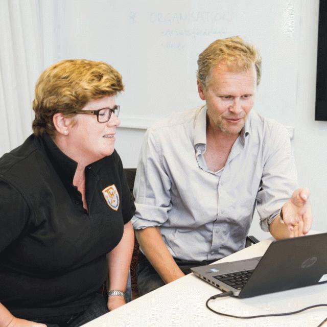 Two people sitting in front of a laptop.