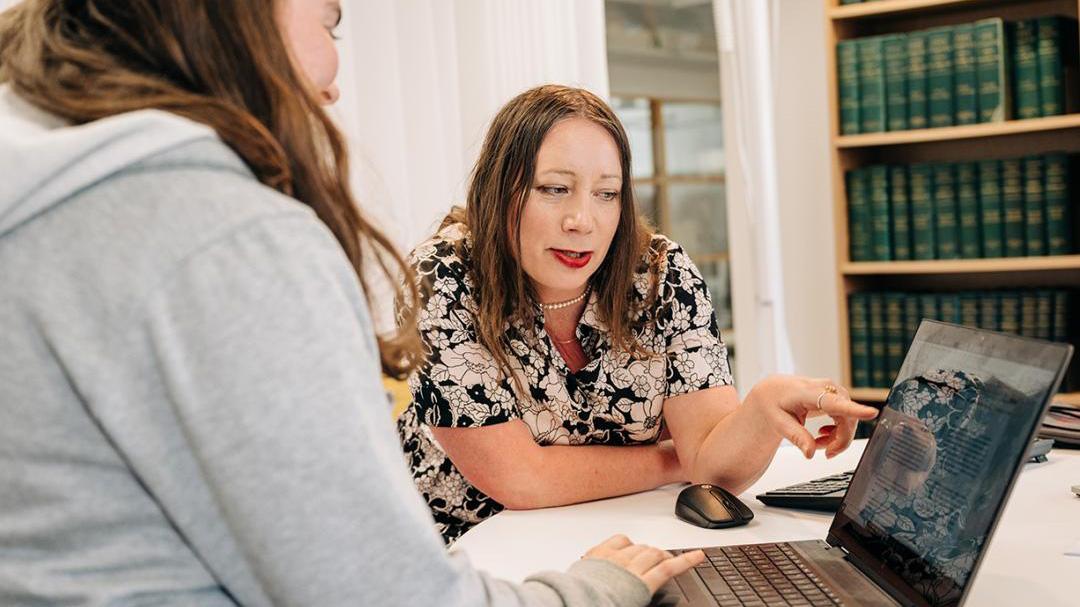 Two women sitting in front of a laptop.