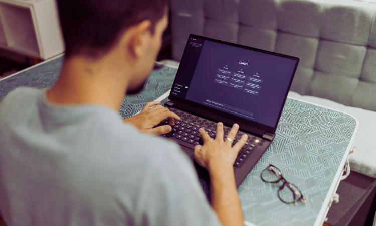 Manlig person som sitter vid en laptop och söker på ChatGPT