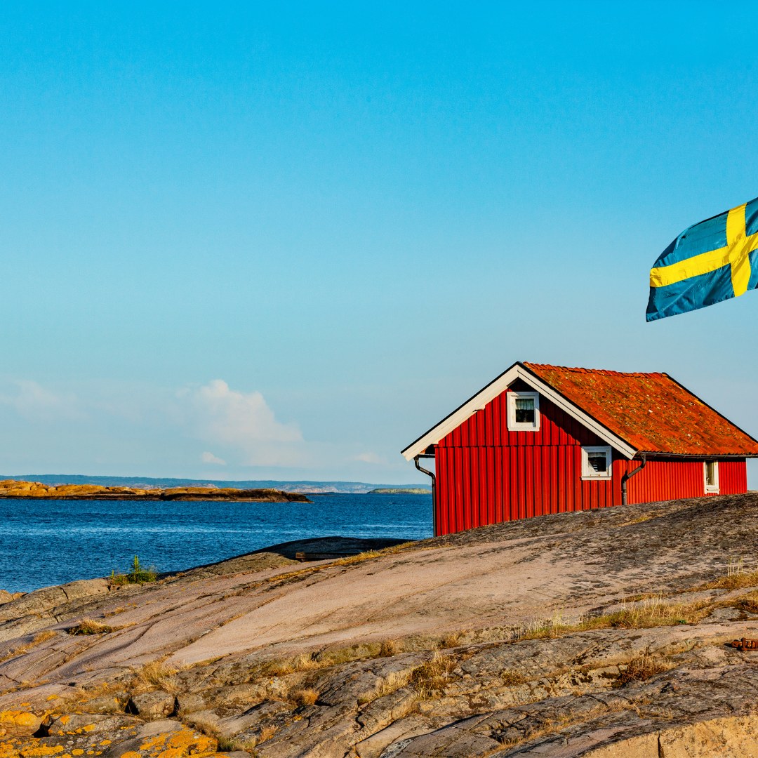 Röd stuga, blå himmel och hav